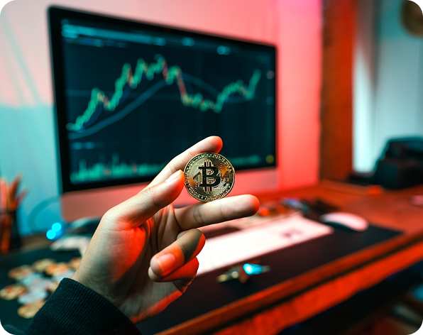 Hand holding Bitcoin with trading screens in background